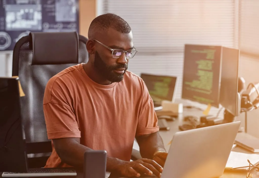 An cybersecurity employee sits at a desk working on his laptop