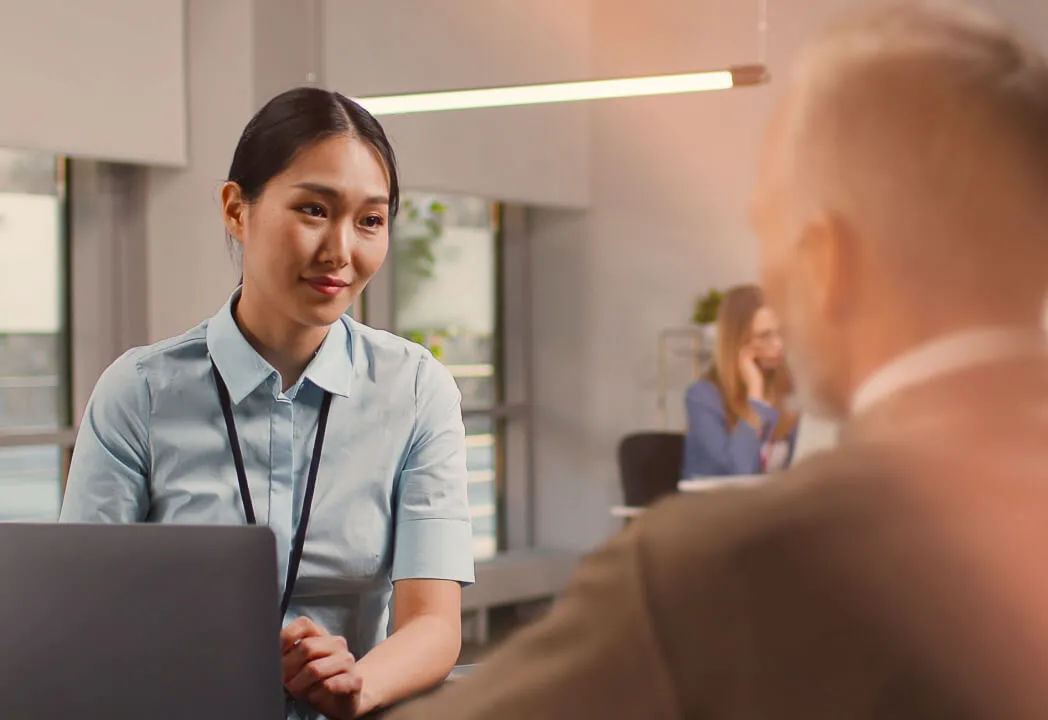 A smiling bank employee speaks to a customer